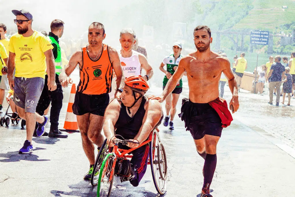 Grupo de corredores de rua em movimento durante uma prova ao ar livre, vestindo roupas esportivas leves e coloridas. A imagem mostra atletas de diferentes perfis correndo juntos, com foco na energia, determinação e espírito coletivo, em um cenário urbano ao fundo.