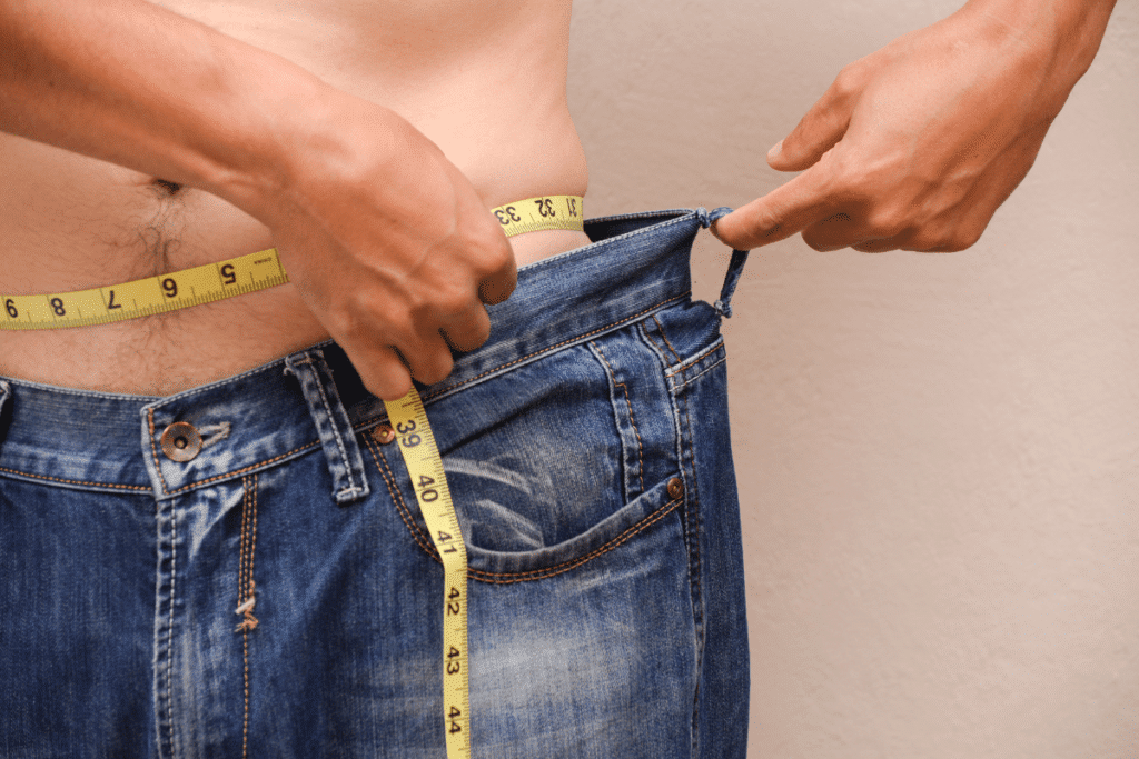 Homem medindo a circunferência abdominal para avaliar a redução de gordura corporal e o emagrecimento.
