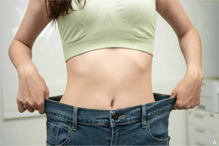 Mulher mostrando a calça folgada na cintura como resultado do emagrecimento.