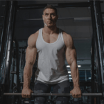 Pessoa treinando musculação na academia, realizando exercício com pesos e mantendo postura firme, demonstrando foco, força e dedicação ao treino de força para ganho de massa muscular e melhora da performance física.