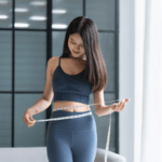 Mulher realizando a aferição da circunferência abdominal como indicador de redução de medidas.