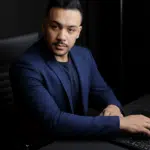 Alef Douglas, nutricionista esportivo e personal trainer, sentado à mesa trabalhando no notebook, planejando estratégias de saúde, performance e gestão no mercado fitness.